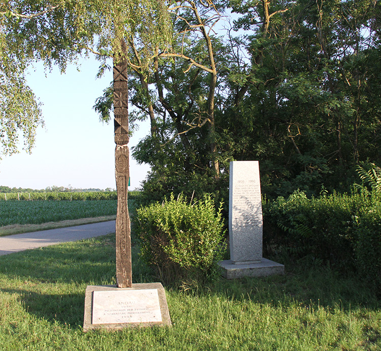 Gedenkstein und Skulptur aus Holz mit Gedenktafel an der Fluchtstraße in Andau